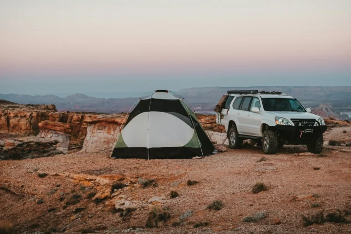 Tent and SUV at a campsite on red rock at dusk