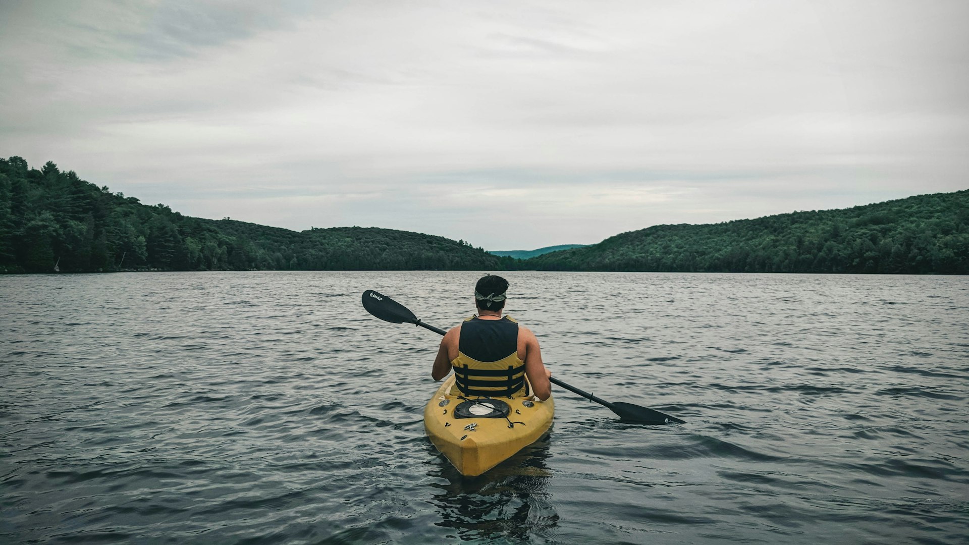 Paddler in a yellow kayak on a calm lake
