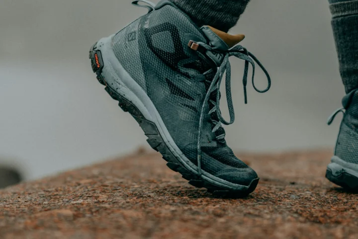 Close-up of a hiker stepping onto rock in mid-height hiking boots
