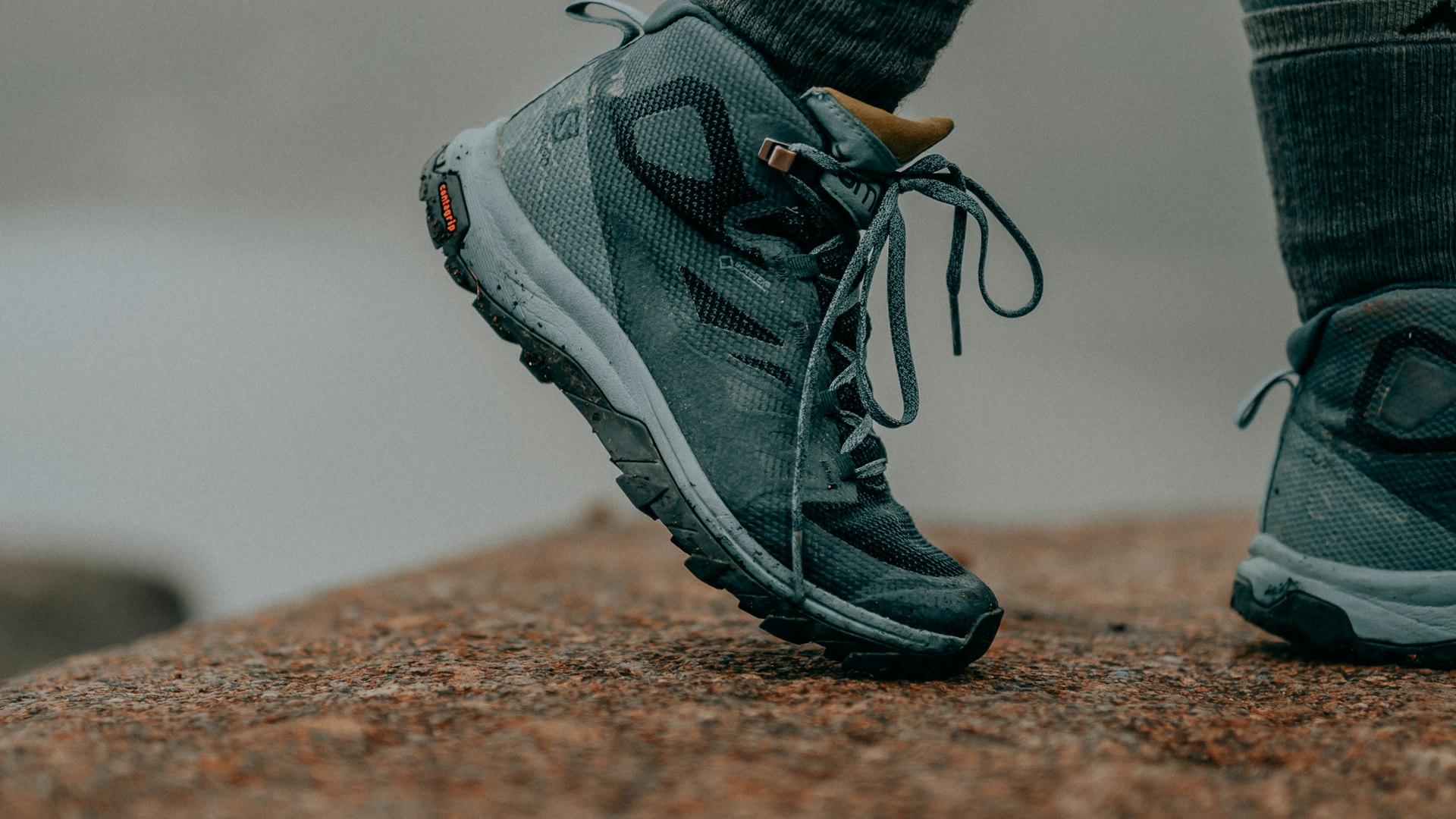 Close-up of a hiker stepping onto rock in mid-height hiking boots