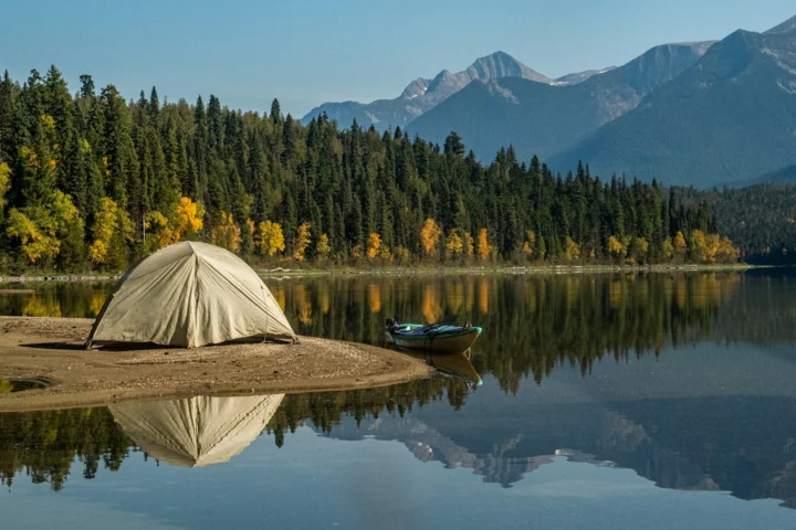 Tent on a small beach at a mountain lake with a canoe beside it