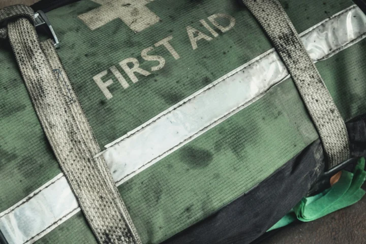 Worn green first aid bag with reflective strip and straps