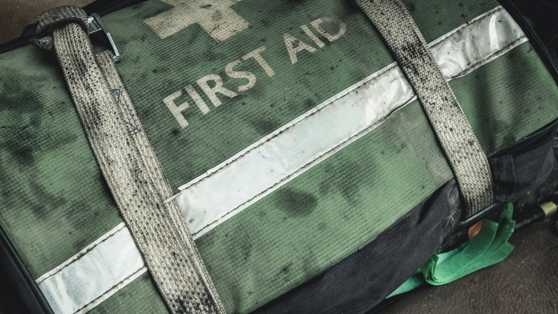 Worn green first aid bag with reflective strip and straps