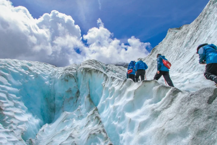 Roped climbers in helmets moving up a glacier
