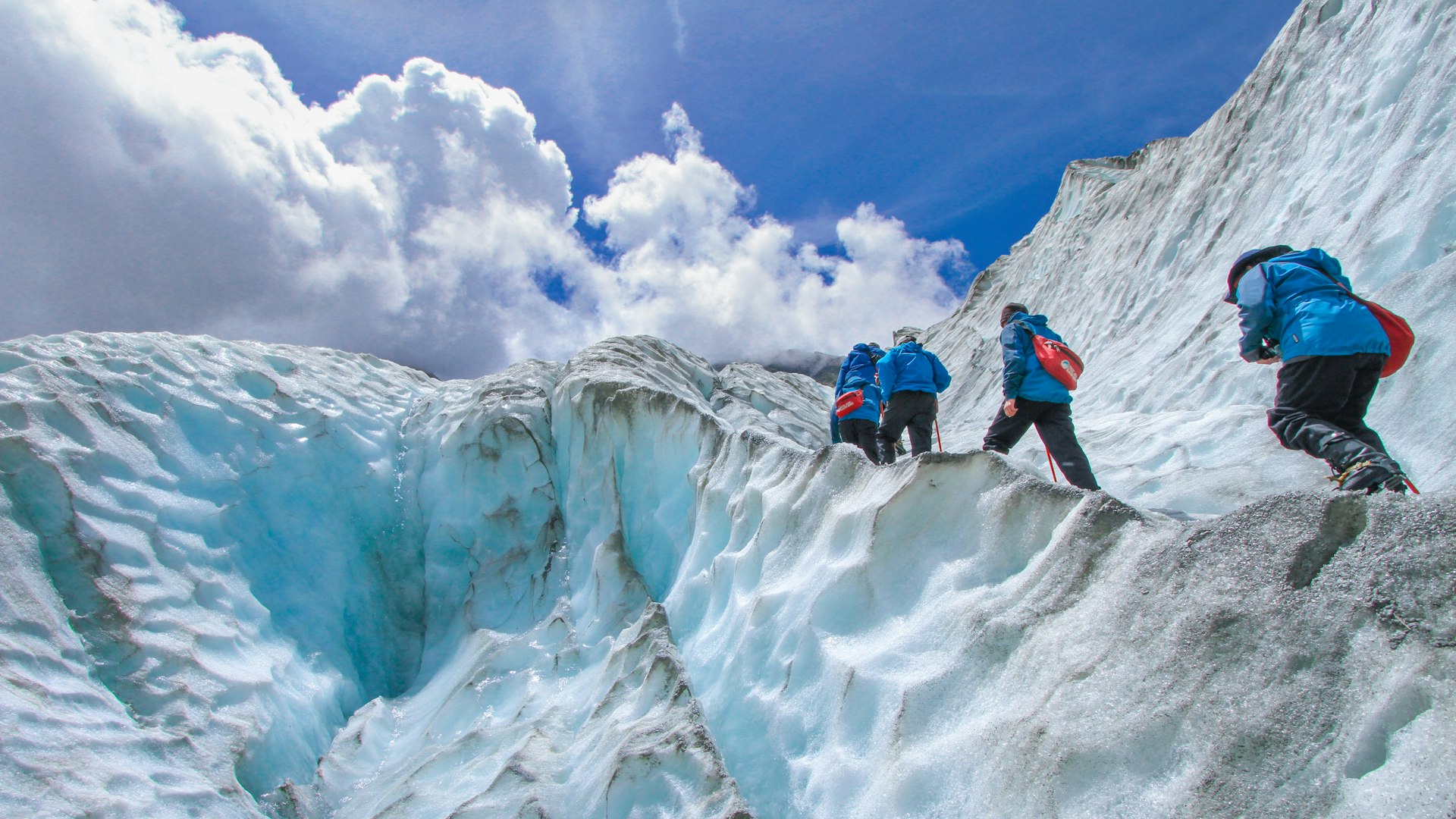 Roped climbers in helmets moving up a glacier
