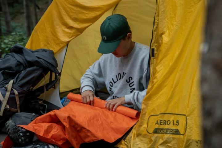 Camper rolling up a sleeping pad in a tent doorway
