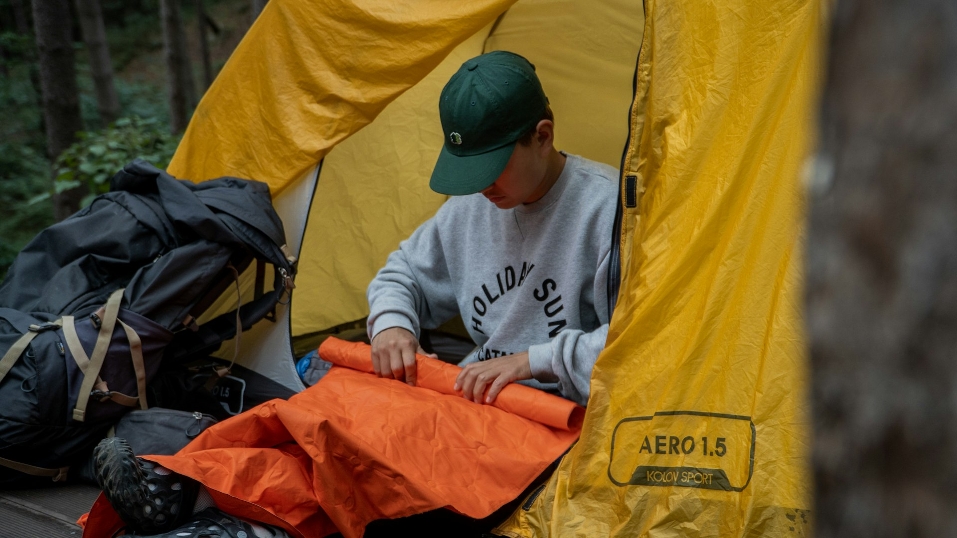 Camper rolling up a sleeping pad in a tent doorway
