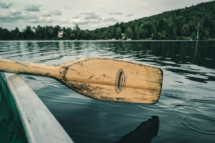 Wooden paddle resting across a canoe on a lake